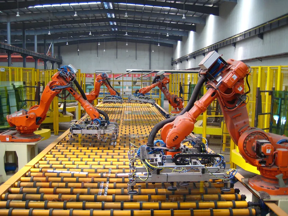 ABB arms with suction frames lifting glass sheets off a production line; the controller keeps each tool on its planned path