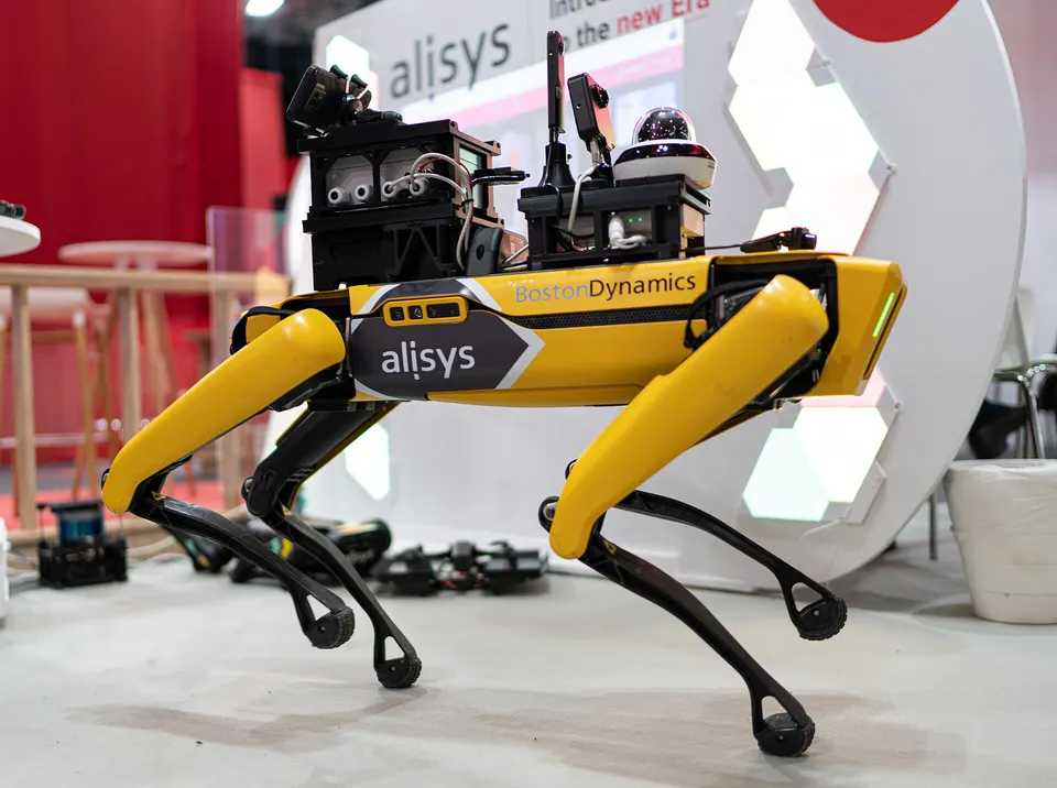 Spot carrying a sensor payload, lidar and a pan-tilt camera, bolted to the rails on its back