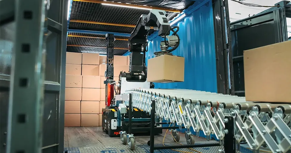 Stretch unloading a container: a suction-cup gripper lifts each box onto a conveyor while the wheeled base drives in