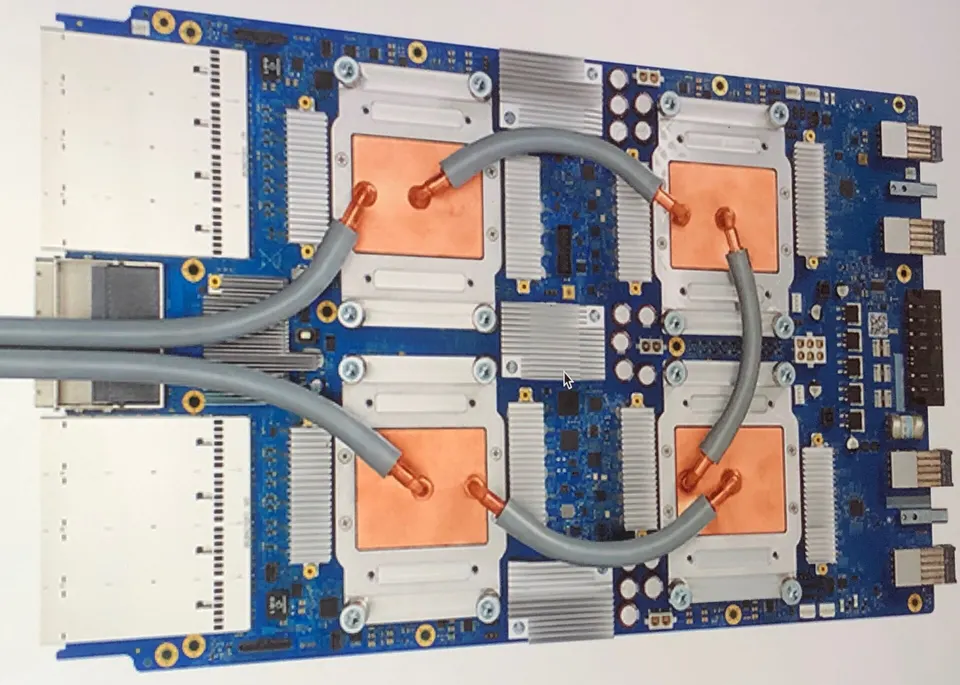 A TPU v3 board: four chips under copper water-cooling plates, with pipes carrying the coolant