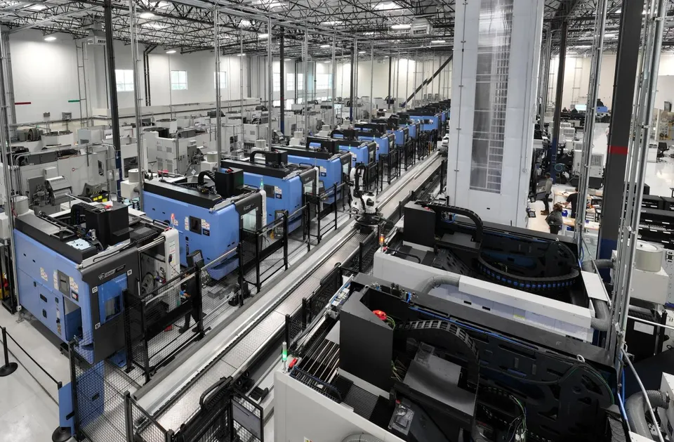 Rows of CNC machining centres inside a Hadrian factory, fed and linked by automation that moves parts between machines