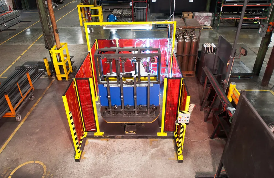 A robot welding cell behind safety screens in a steel shop: the same kind of cell Path fits with its scanning and seam-finding software