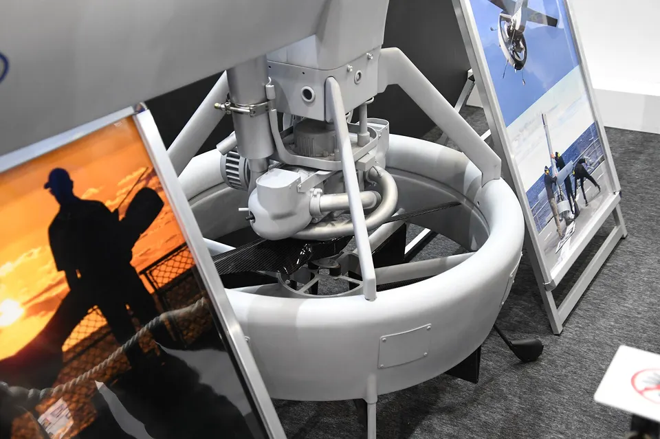 The tail end of a V-BAT: a small two-cylinder engine spins one fan inside a ring-shaped duct, which lifts it standing up and pushes it once it tips over