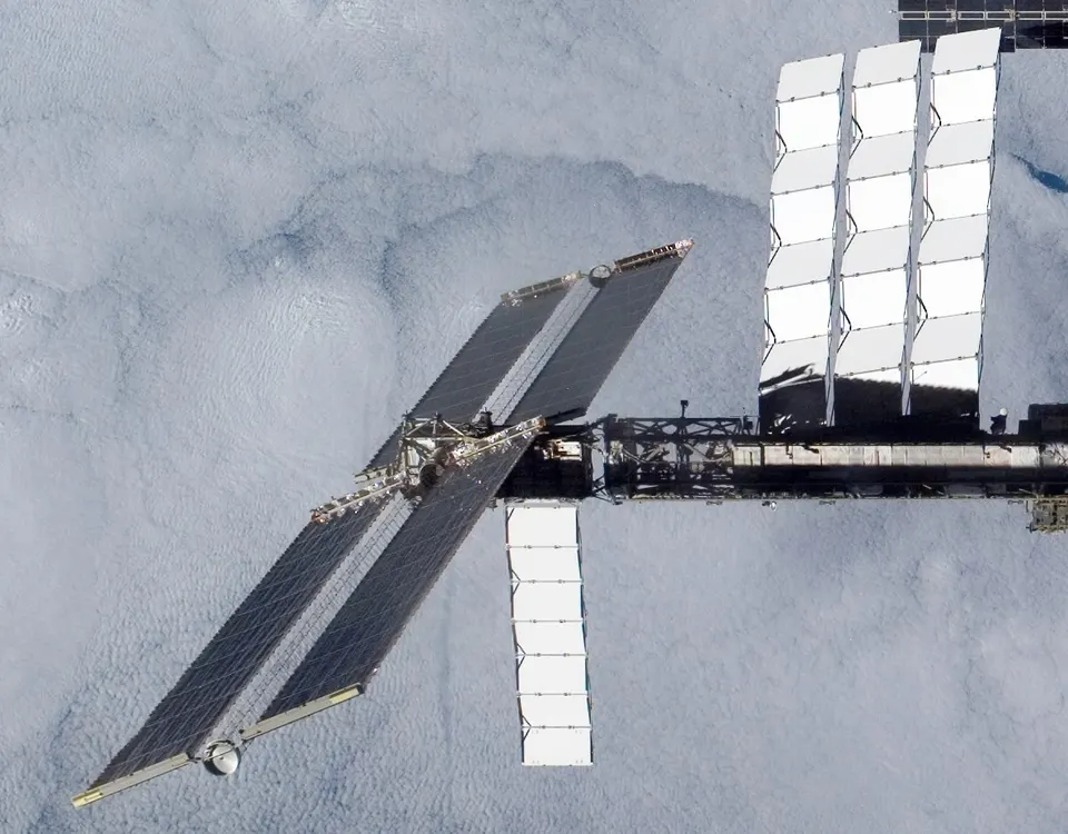 Solar wings and white radiator panels on the ISS, not Starcloud: sunlight in, waste heat shed to space, the same trade an orbital data center makes