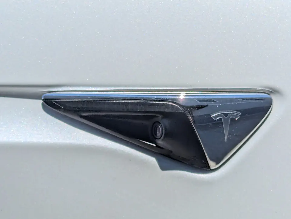 One of the eight cameras FSD drives with: a side camera set into a Tesla's front fender, looking backwards