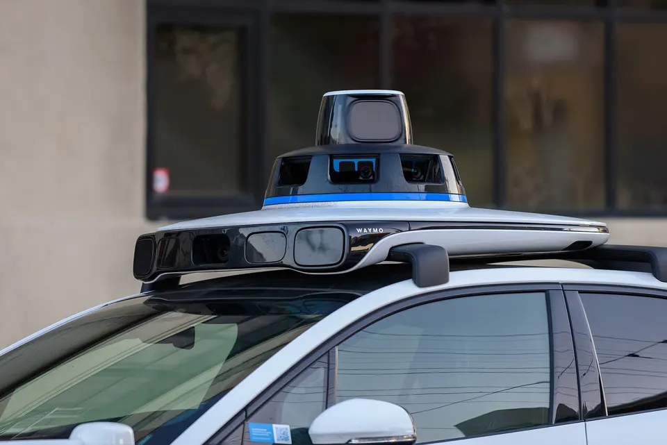 The sensor dome on a Waymo Jaguar: a spinning lidar on top, cameras and radar around it, seeing 360° day and night