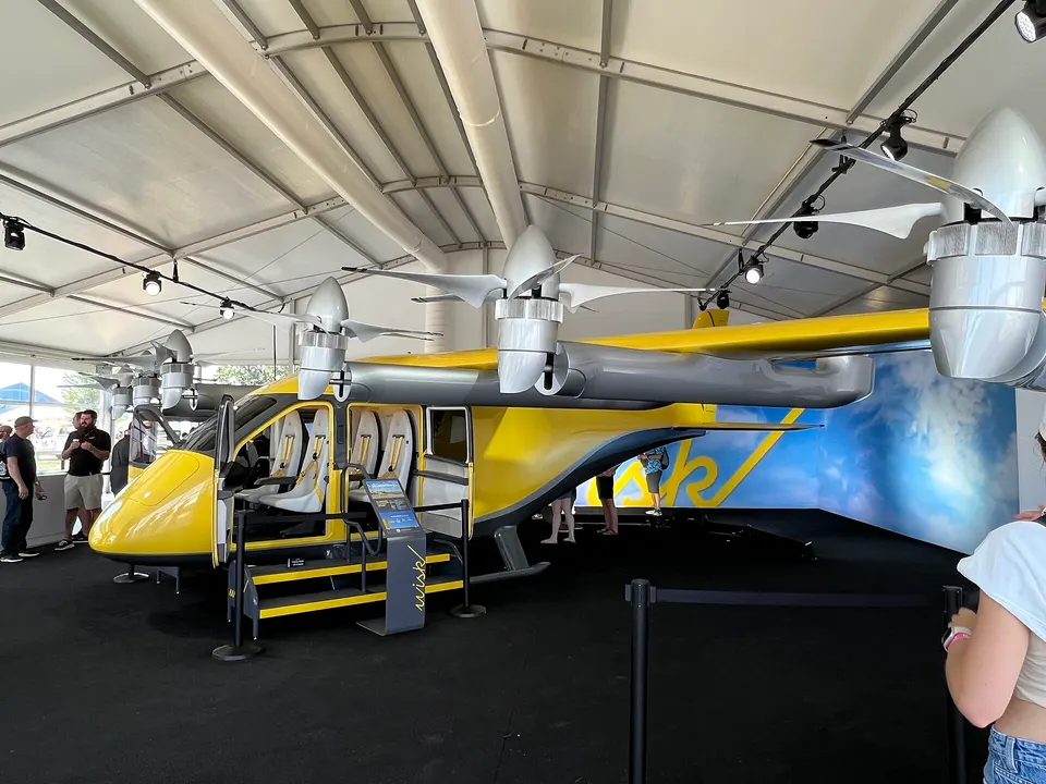 A full-size Gen 6 mockup: twelve propellers on booms, the front six tilt forward for cruise, and the cabin has four seats and no pilot's controls